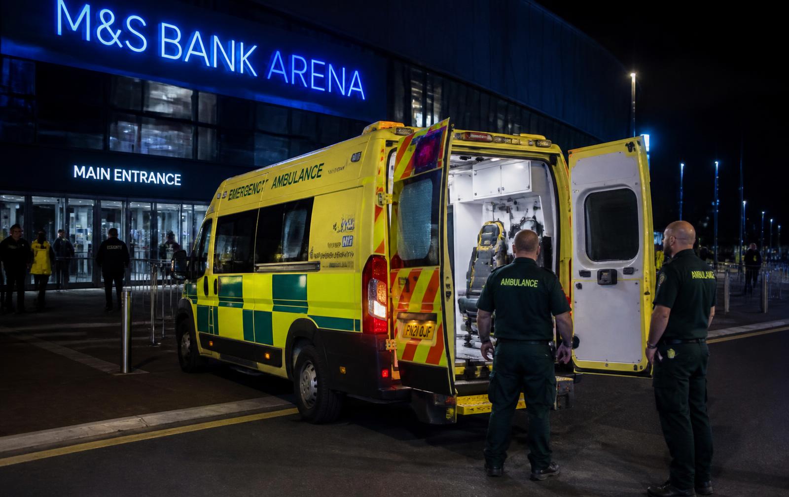 Emergency ambulance on standby outside a UK arena at night